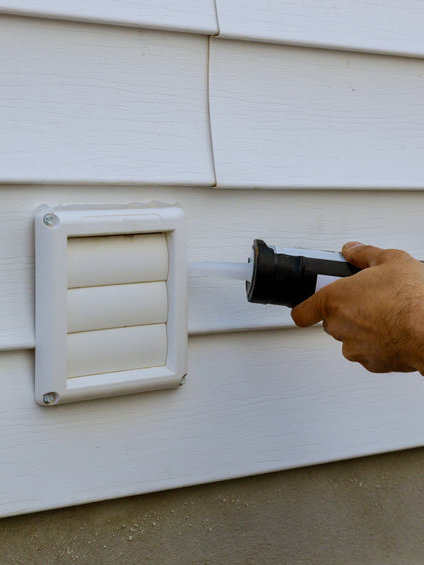 Laundry the white frame of exhaust fan dryer fans with a silicone gun in an apartment building trim